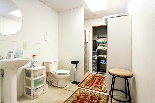 bathroom with concrete flooring, a shower with shower door, and toilet