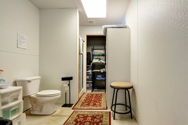 bathroom with a shower with shower door and toilet