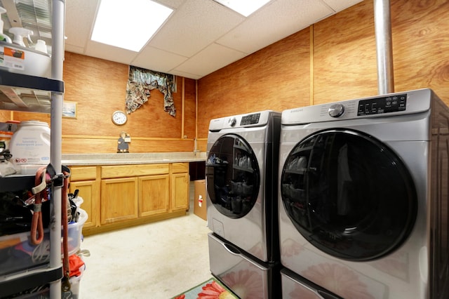 laundry area featuring cabinets, wood walls, and washing machine and clothes dryer