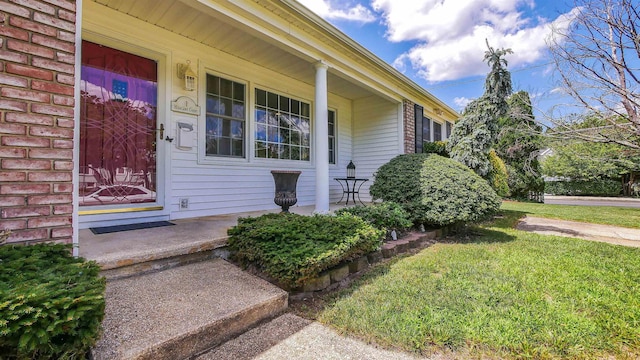 property entrance featuring a lawn and covered porch