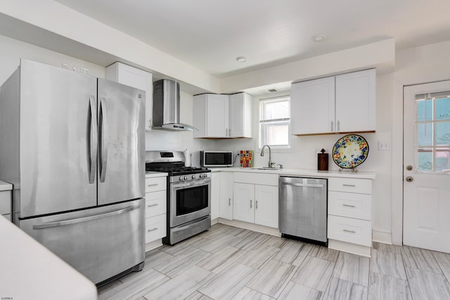 kitchen featuring wall chimney exhaust hood, stainless steel appliances, and white cabinets