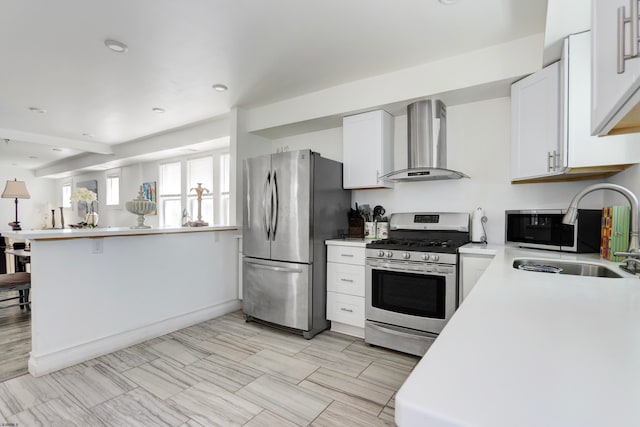 kitchen with wall chimney exhaust hood, white cabinetry, appliances with stainless steel finishes, and sink