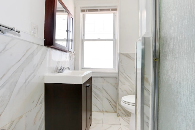 bathroom with a shower with door, vanity, toilet, and plenty of natural light