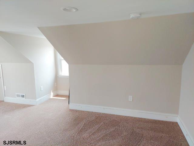 bonus room featuring vaulted ceiling and light colored carpet