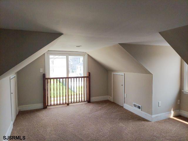 additional living space featuring carpet floors and vaulted ceiling