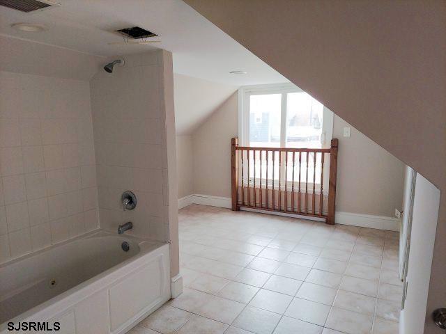 bathroom with tiled shower / bath and vaulted ceiling