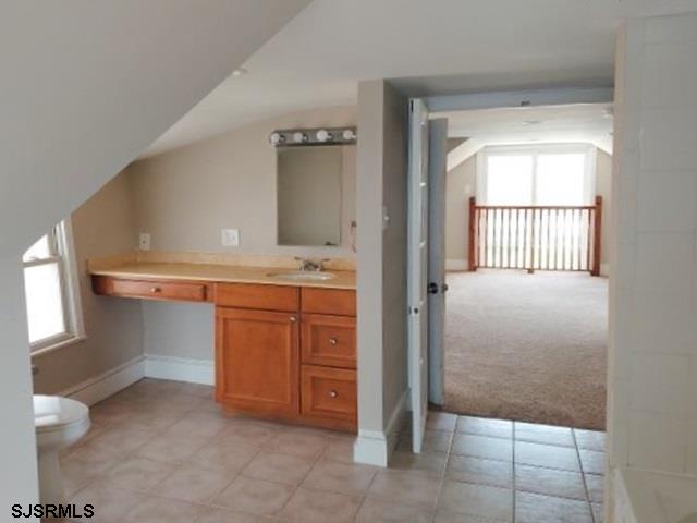 bathroom with lofted ceiling, vanity, and toilet