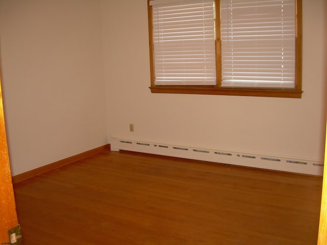 empty room featuring wood-type flooring and baseboard heating