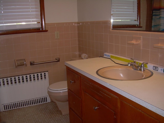 bathroom with tile walls, radiator, vanity, and toilet