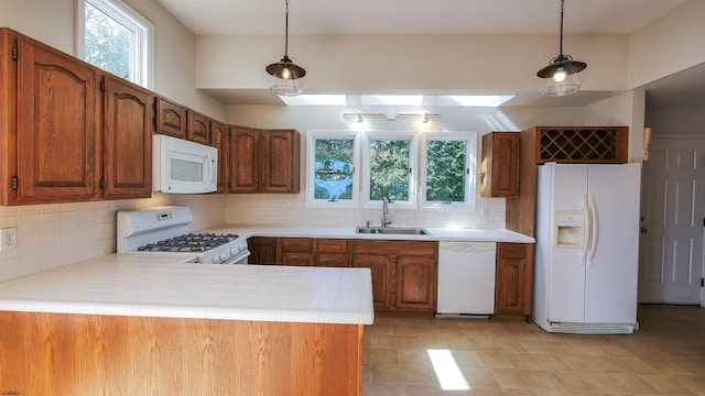 kitchen featuring kitchen peninsula, sink, white appliances, tasteful backsplash, and decorative light fixtures