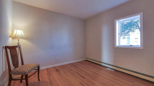 sitting room with a baseboard radiator and wood-type flooring