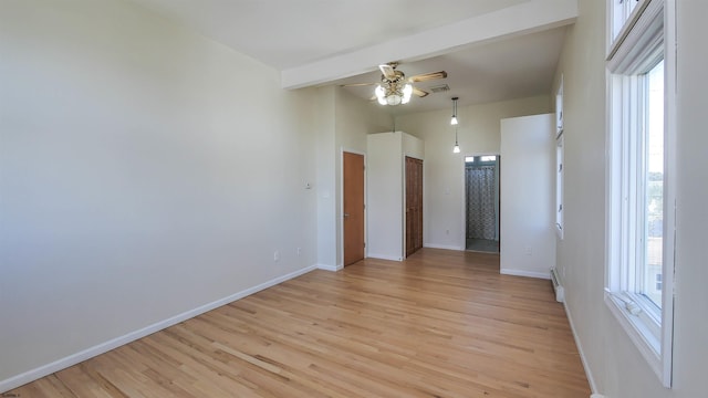 empty room featuring a baseboard heating unit, ceiling fan, light hardwood / wood-style flooring, and beamed ceiling