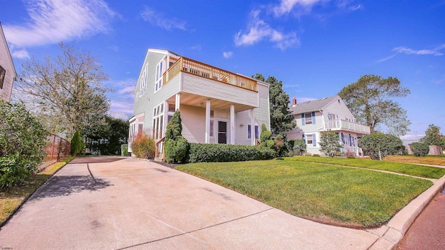 view of front of home with a balcony and a front yard