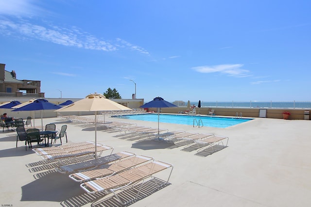 view of swimming pool featuring a patio and a water view