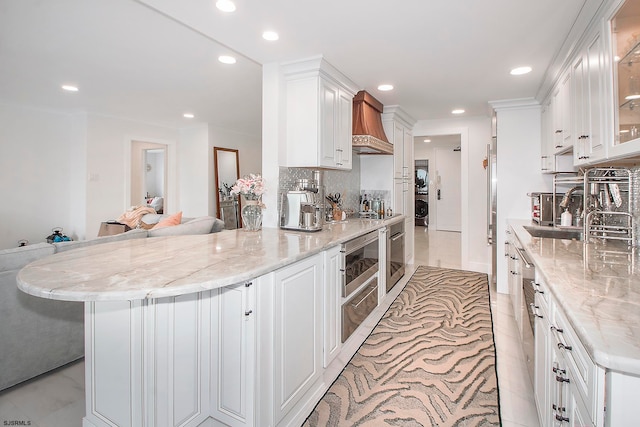 kitchen with white cabinets, light stone counters, and premium range hood