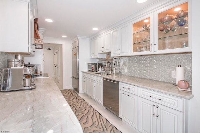 kitchen with light stone countertops, decorative backsplash, white cabinetry, and appliances with stainless steel finishes