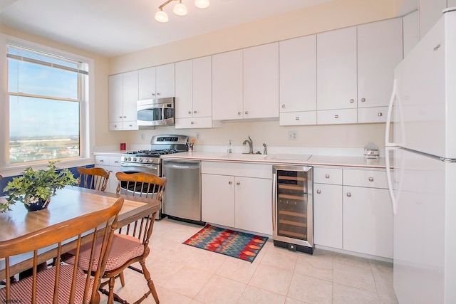 kitchen with appliances with stainless steel finishes, white cabinetry, beverage cooler, and sink