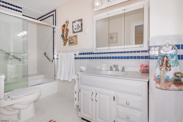 full bathroom with shower / bath combination with glass door, vanity, tile patterned floors, tile walls, and toilet