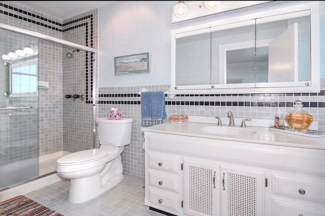 bathroom with tile walls, tile patterned flooring, a shower with shower door, vanity, and toilet