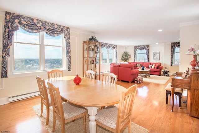 dining space featuring ornamental molding, a baseboard heating unit, and light hardwood / wood-style flooring