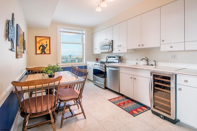 kitchen featuring wine cooler, light tile patterned floors, sink, white cabinetry, and stainless steel appliances