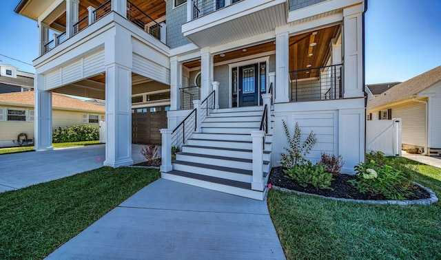 entrance to property with a balcony, a garage, a porch, and a lawn