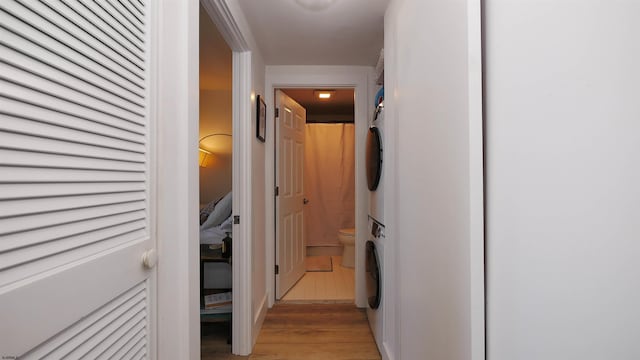 hallway featuring stacked washer and clothes dryer and light hardwood / wood-style floors