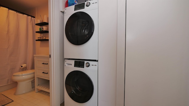 laundry area featuring stacked washer and clothes dryer and light tile patterned floors