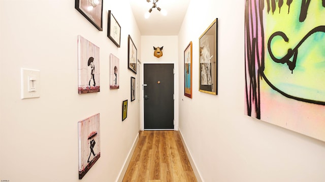 corridor with light wood-type flooring and baseboards