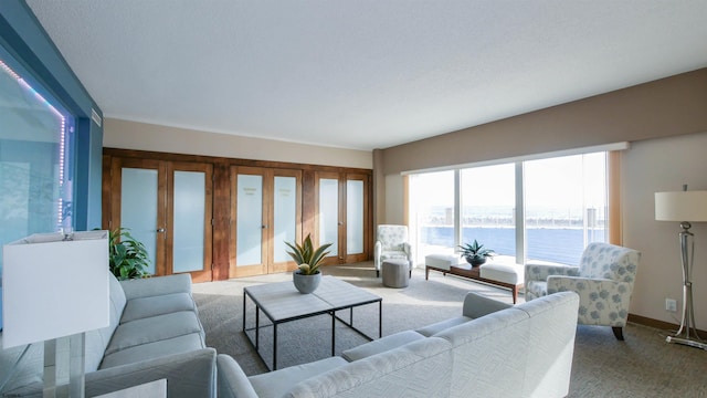 living room featuring carpet floors, a textured ceiling, french doors, and a water view