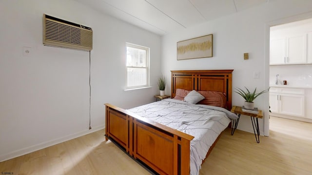 bedroom featuring an AC wall unit and light hardwood / wood-style flooring