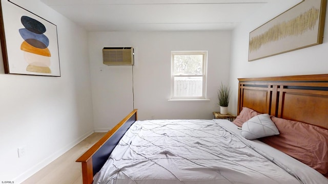 bedroom featuring light wood-type flooring and an AC wall unit