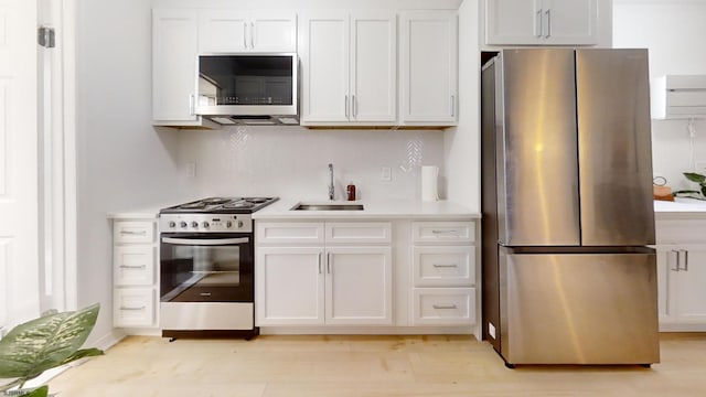 kitchen with light wood-type flooring, sink, white cabinets, decorative backsplash, and appliances with stainless steel finishes