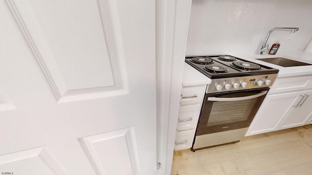 kitchen with sink, light wood-type flooring, white cabinetry, and stainless steel range oven