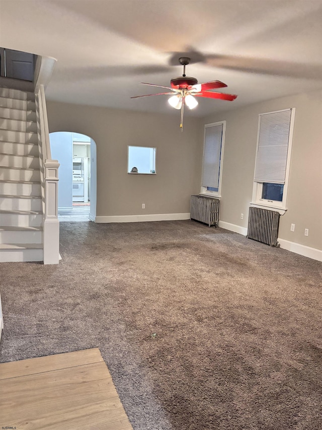 unfurnished living room with ceiling fan, radiator, and carpet floors