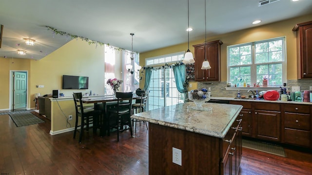 kitchen with pendant lighting, tasteful backsplash, a kitchen island, and dark hardwood / wood-style flooring