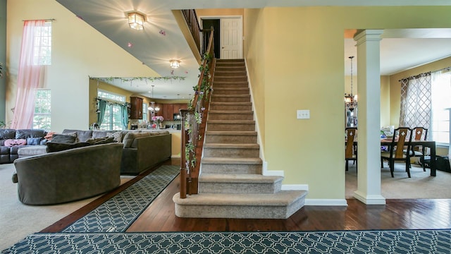 staircase with a wealth of natural light, wood-type flooring, and decorative columns