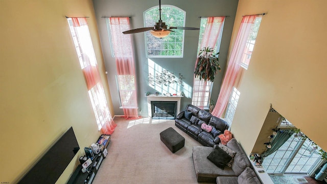 carpeted living room featuring a towering ceiling and ceiling fan