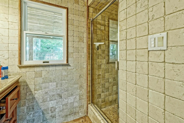 bathroom with walk in shower, vanity, and brick wall