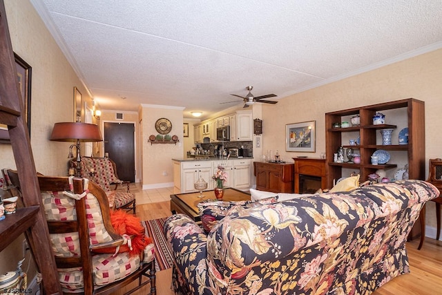 living room featuring ornamental molding, light wood-type flooring, a textured ceiling, and ceiling fan