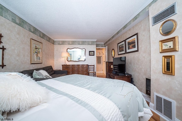 bedroom with a textured ceiling, wood-type flooring, and ornamental molding