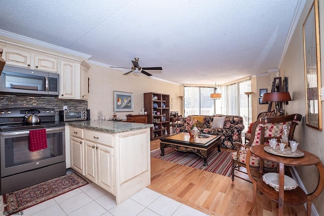 kitchen with light hardwood / wood-style floors, ceiling fan, stainless steel appliances, crown molding, and cream cabinets