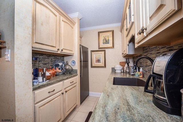 kitchen featuring sink, stainless steel refrigerator, light tile patterned floors, ornamental molding, and light brown cabinetry