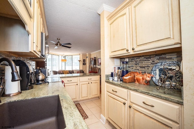 kitchen featuring tasteful backsplash, a textured ceiling, ceiling fan, ornamental molding, and sink