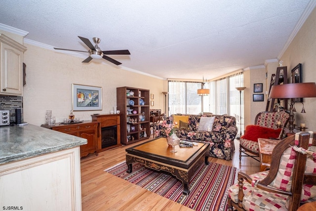 living room featuring a textured ceiling, light hardwood / wood-style floors, ceiling fan, and crown molding