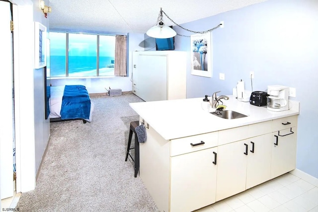 kitchen featuring white cabinets, sink, a textured ceiling, decorative light fixtures, and light carpet