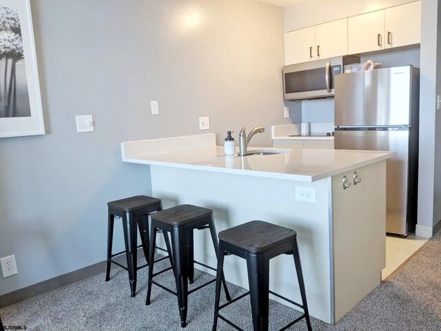 kitchen with sink, stainless steel appliances, kitchen peninsula, and a kitchen breakfast bar