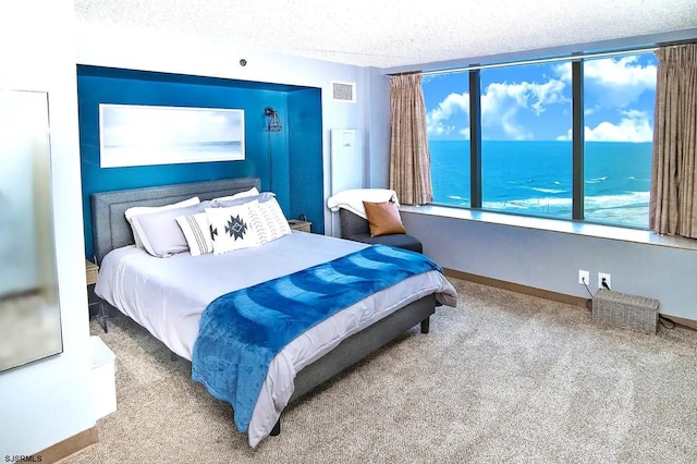 carpeted bedroom featuring a textured ceiling and a water view