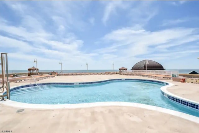 view of swimming pool featuring a water view and a patio area