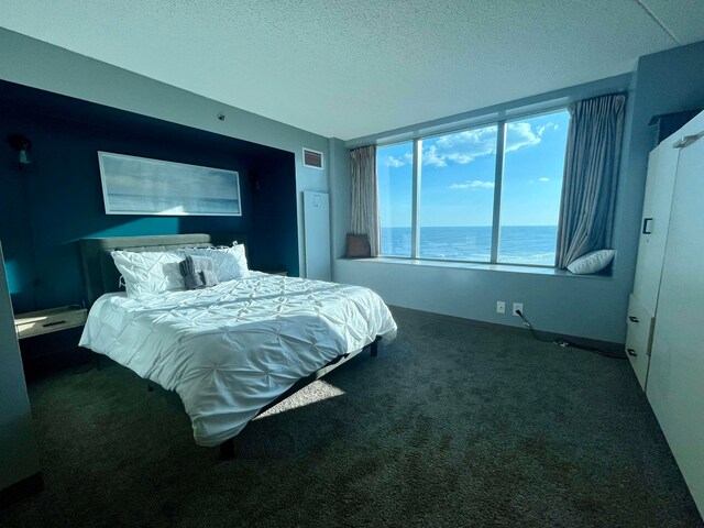 carpeted bedroom featuring a textured ceiling and a water view